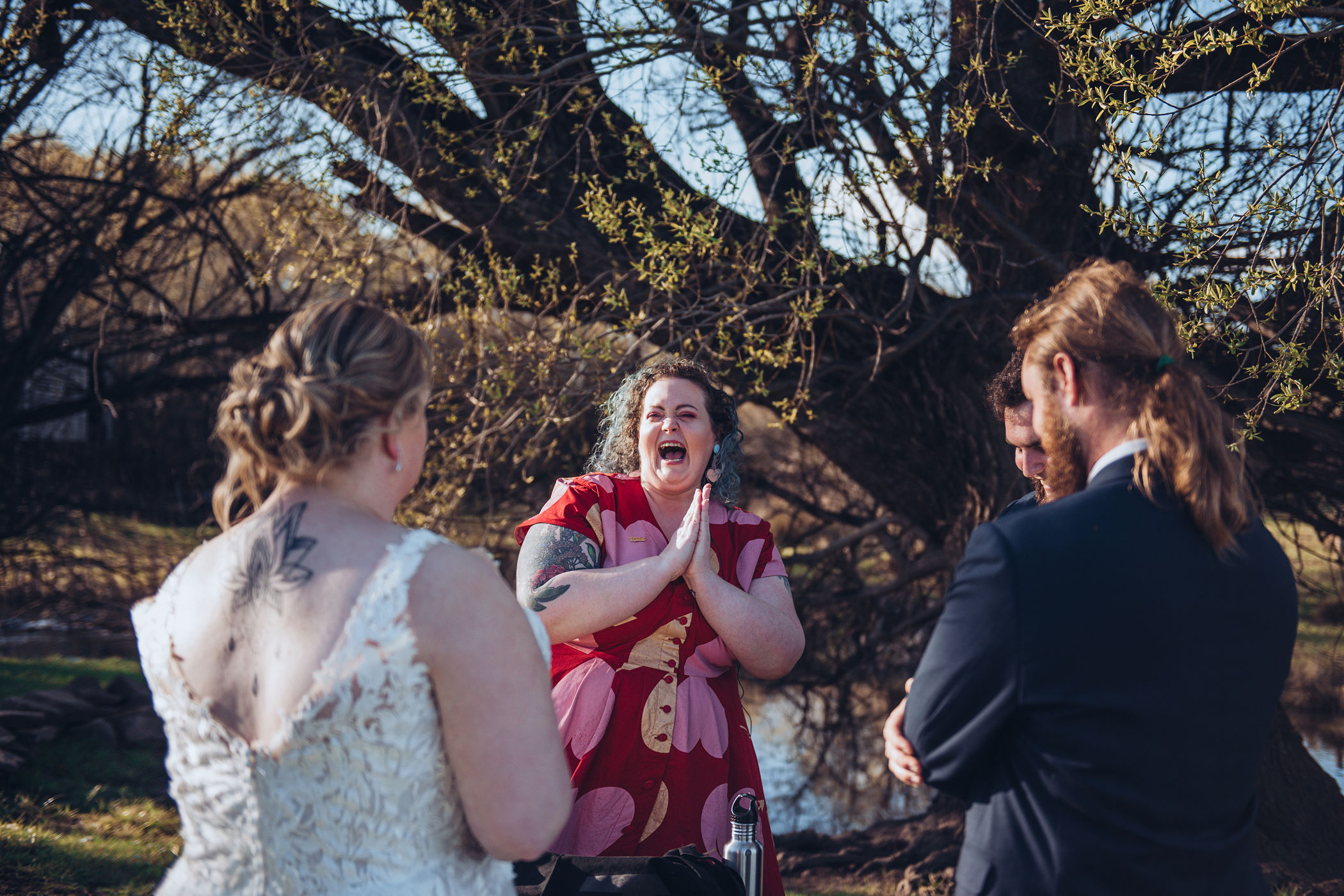 a candid moment caught on camera of the colourful celebrant cackling with glee post-ceremony at the signing table, hands clasped together